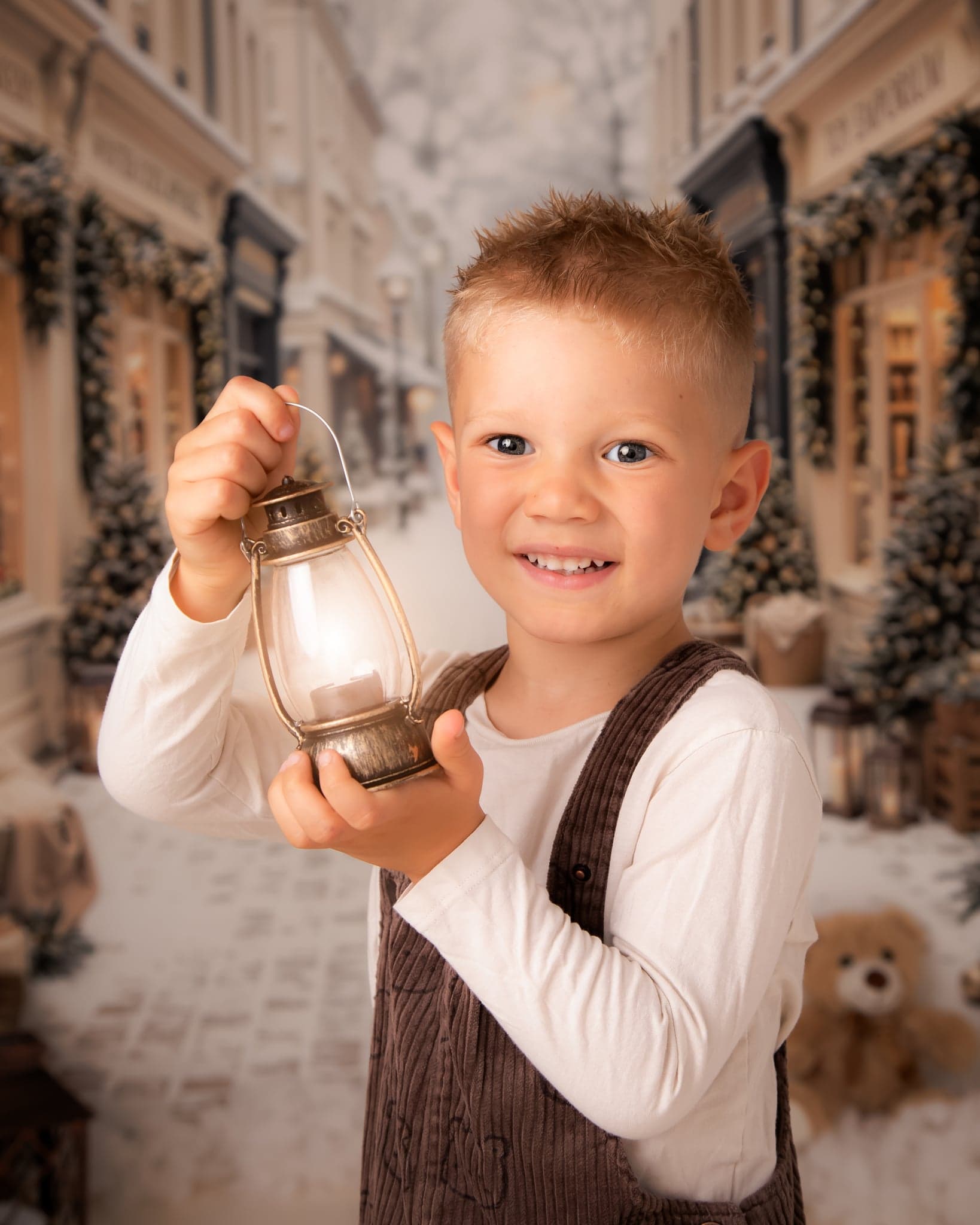 A smiling boy holding a glowing lantern on the Christmas street set.