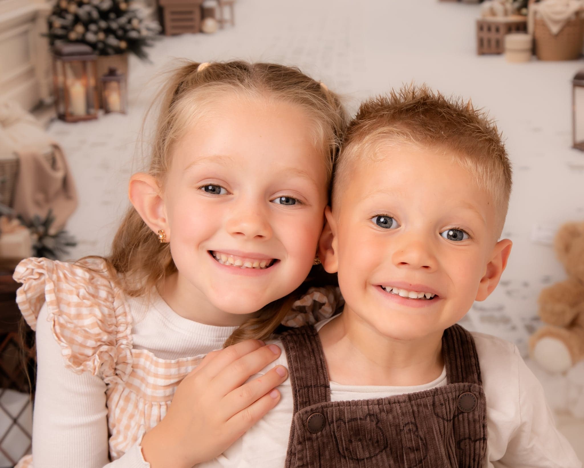Two children smiling together for a festive Christmas portrait.